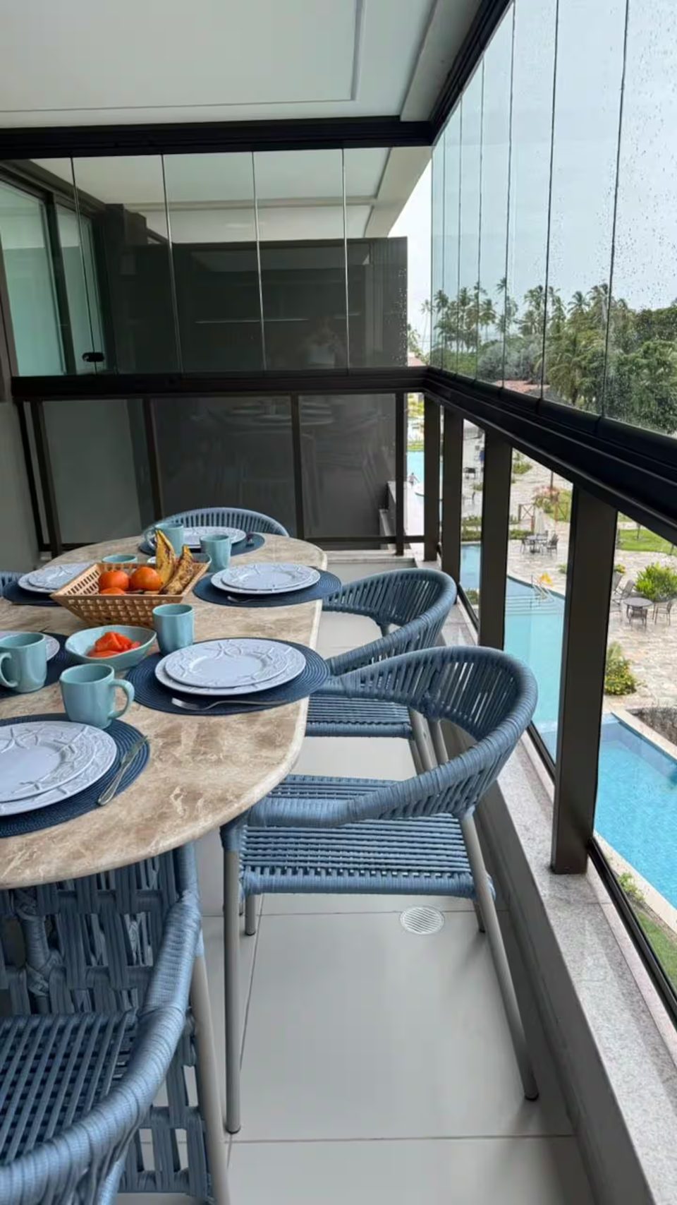 Varanda gourmet do 302D com mesa posta para seis pessoas e vista para a piscina do condomínio.
