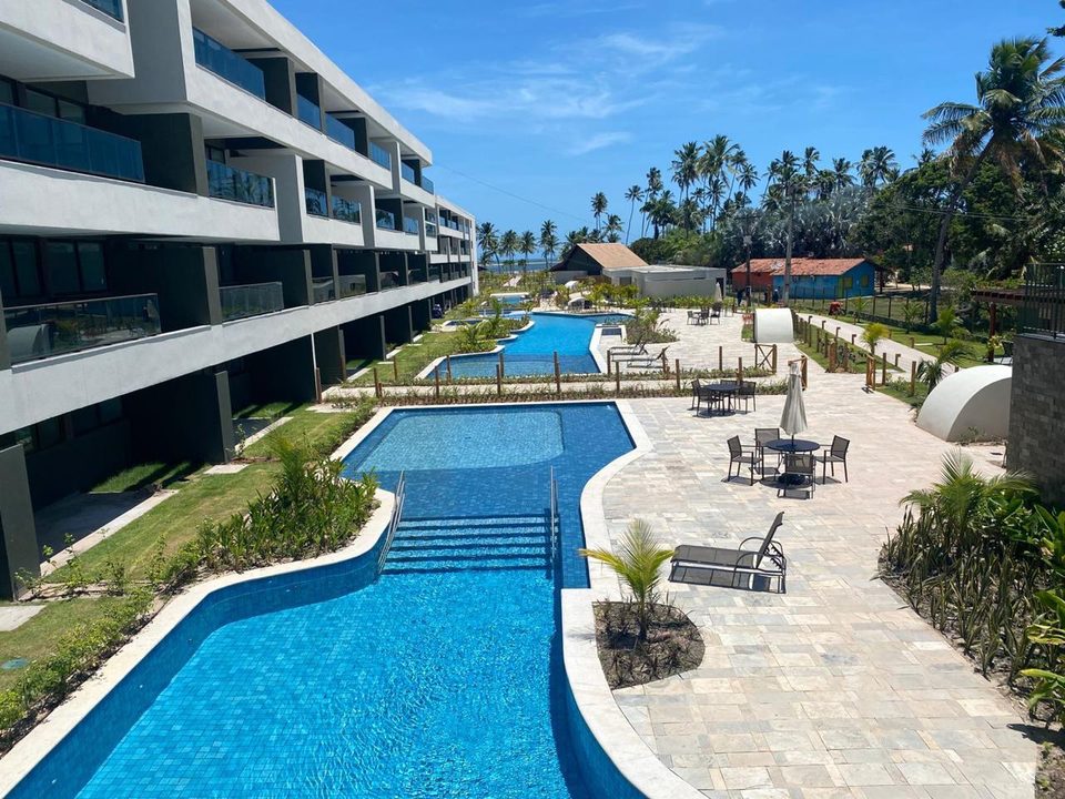 Piscinas em curva do Galápagos Beach Residence durante o dia, com deck e a fachada dos blocos.