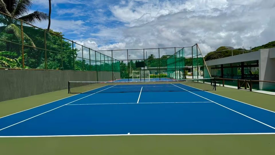 Quadra de tênis do Galápagos Beach Residence cercada por vegetação.